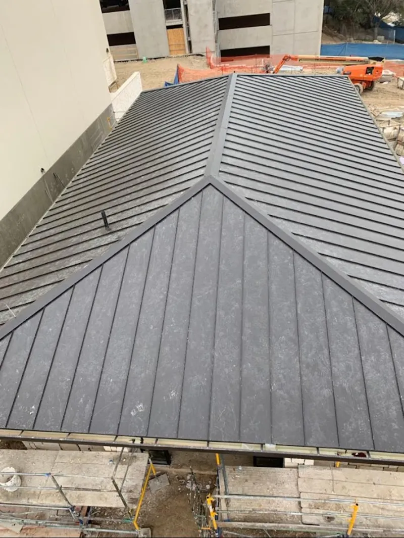 Commercial metal roof construction with crane equipment in Loughman